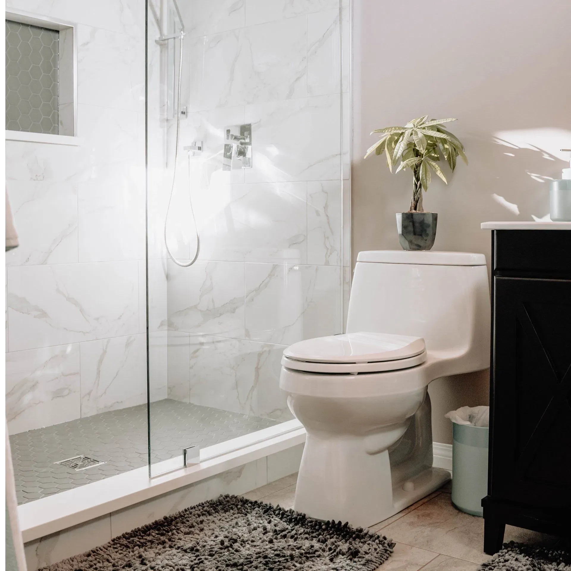 Modern marble bathroom with glass shower and dark vanity
